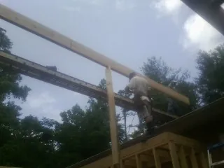 Carpenter setting a ridge beam over a new addition frame — Ice Dam Removal by Roofing Brothers in Central Islip