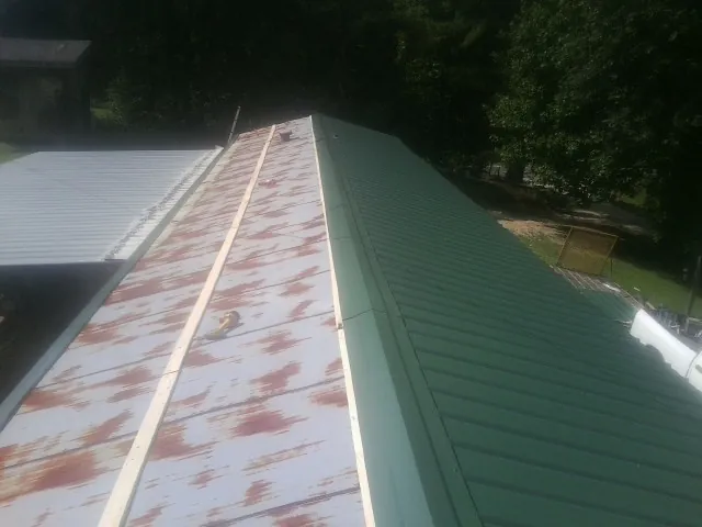 Old rusted panels beside newly installed green metal roofing — Wind Damage Roof Repair by Roofing Brothers in Central Islip