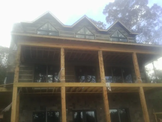 Dormers and porch framing on a large log home under construction — Roof Coating work by our crew in Central Islip