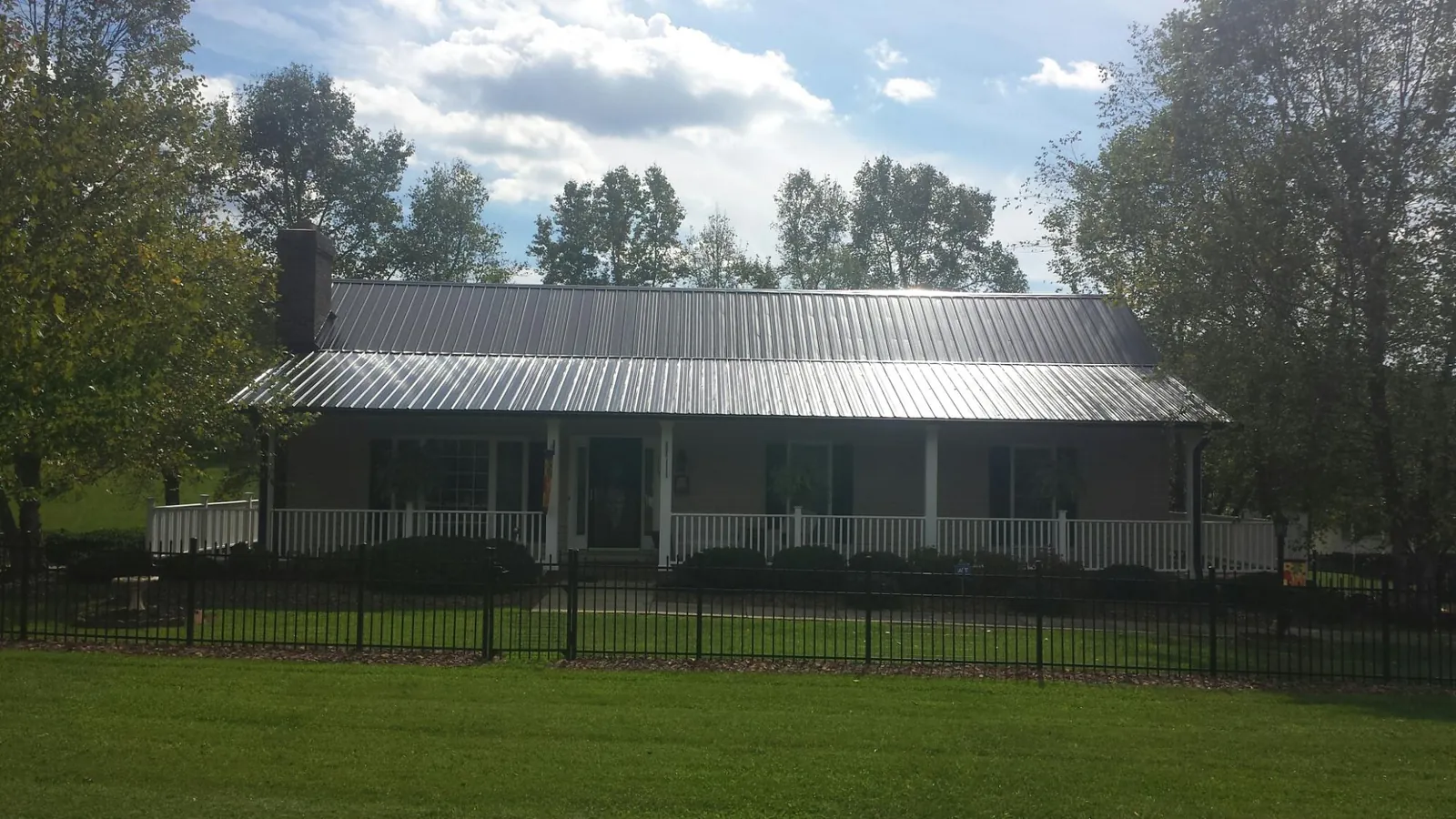 Gray metal roof on a brick ranch with a full width front porch — Gutter Guard Installation work by our crew in Central Islip