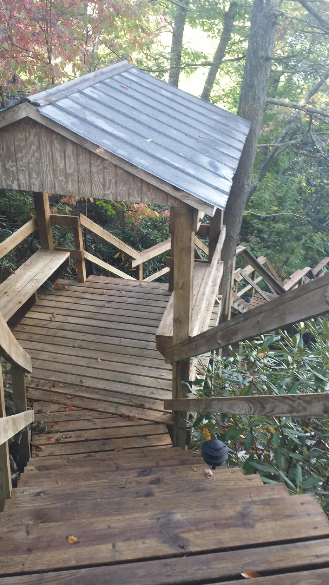Metal roofed shelter over wooden steps on a wooded walkway — Skylight Repair & Installation work by our crew in Central Islip