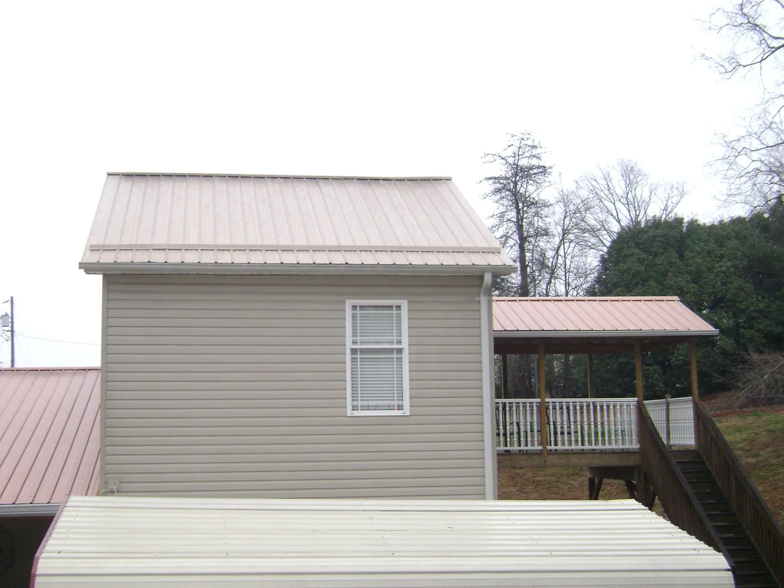 Tan metal roofs on a two story addition and attached porch, from a Roof Replacement job in Central Islip