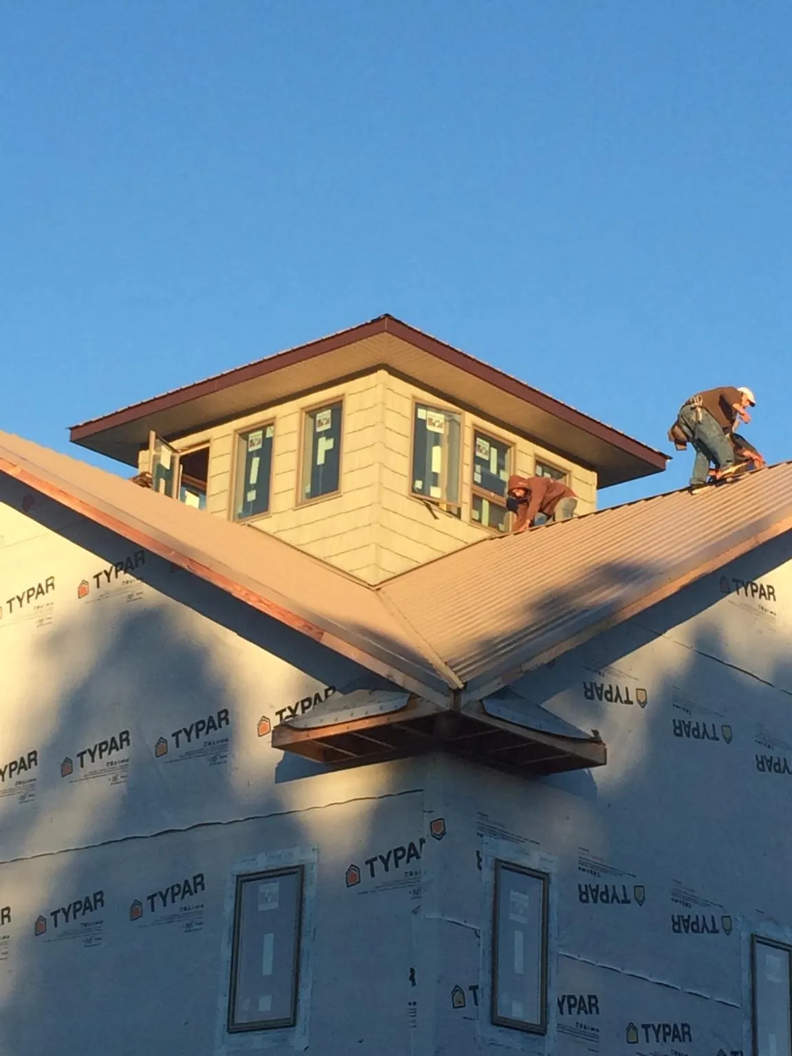 Roofers working around a rooftop cupola on a new metal roof at sunset — Roof Waterproofing in Central Islip by Roofing Brothers